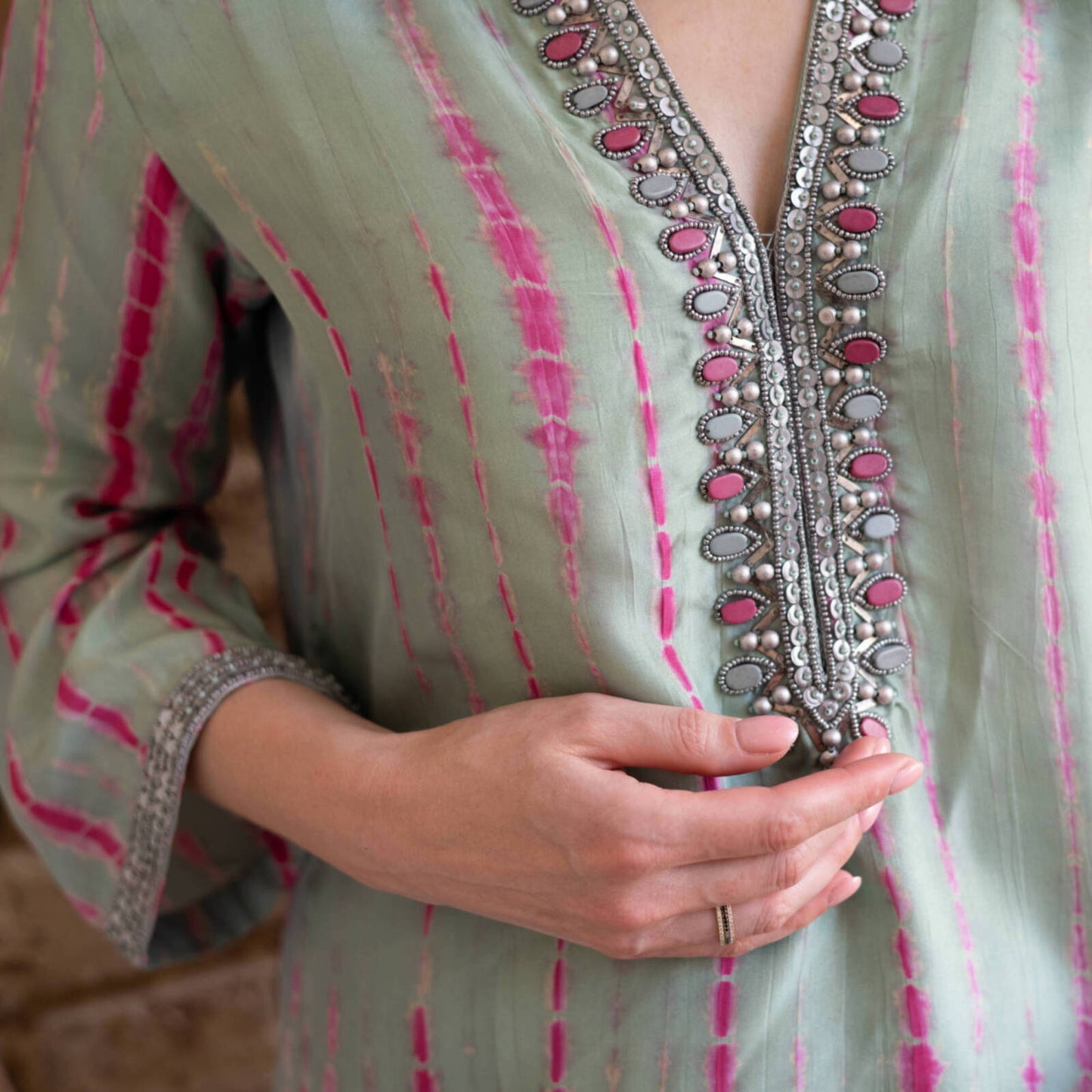 Close-up detail of St Barts sea green and fuchsia tie-dye silk kaftan by Kaminee, showing beaded hand embroidery at neckline
